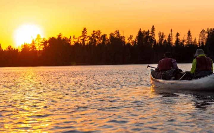 a canoe is paddled into the sunset by two students on an outward bound gap year expedition 